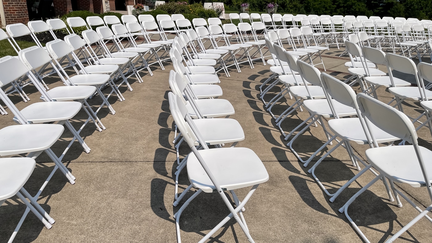 Rows of white folding chairs set for a ceremony